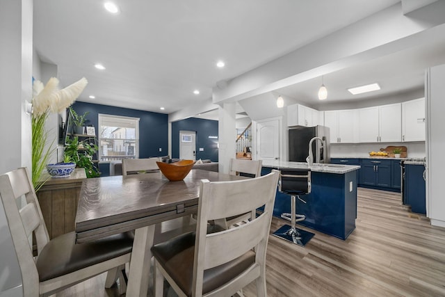 dining area featuring vaulted ceiling, stairway, recessed lighting, and light wood-type flooring