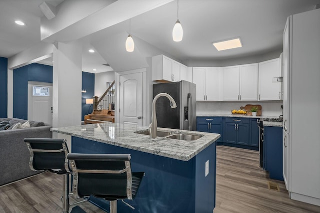 kitchen featuring a kitchen bar, blue cabinetry, a sink, dark wood finished floors, and stainless steel appliances