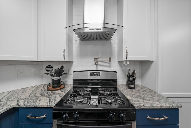 kitchen featuring light stone counters, black range with gas cooktop, white cabinetry, wall chimney exhaust hood, and backsplash