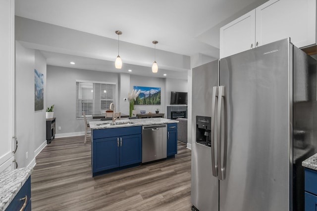 kitchen with blue cabinetry, dark wood-style floors, appliances with stainless steel finishes, and a sink