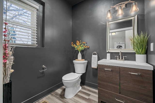 bathroom with baseboards, toilet, vanity, wood finished floors, and washer / clothes dryer