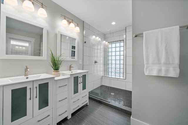 full bath featuring tile patterned floors, two vanities, a walk in shower, and a sink