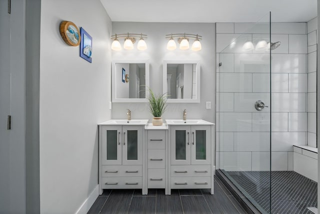 full bath featuring a sink, baseboards, a stall shower, and double vanity