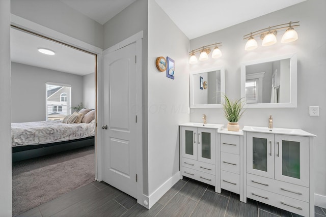 ensuite bathroom featuring a sink, baseboards, ensuite bath, and double vanity