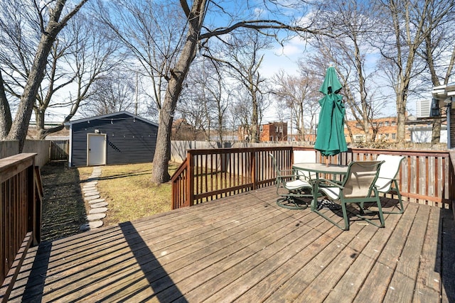 wooden deck featuring outdoor dining space, an outbuilding, and a fenced backyard