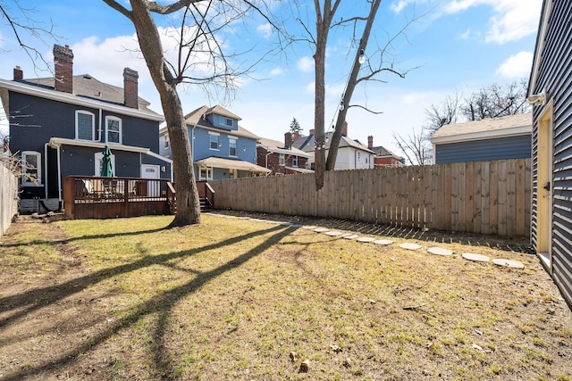 view of yard with a deck, a fenced backyard, and a residential view