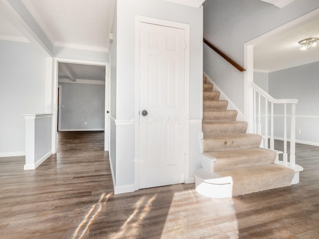 stairs with baseboards, ornamental molding, and wood finished floors