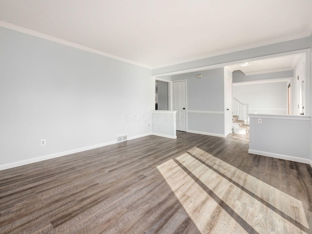 empty room with dark wood-style flooring, visible vents, baseboards, ornamental molding, and stairway