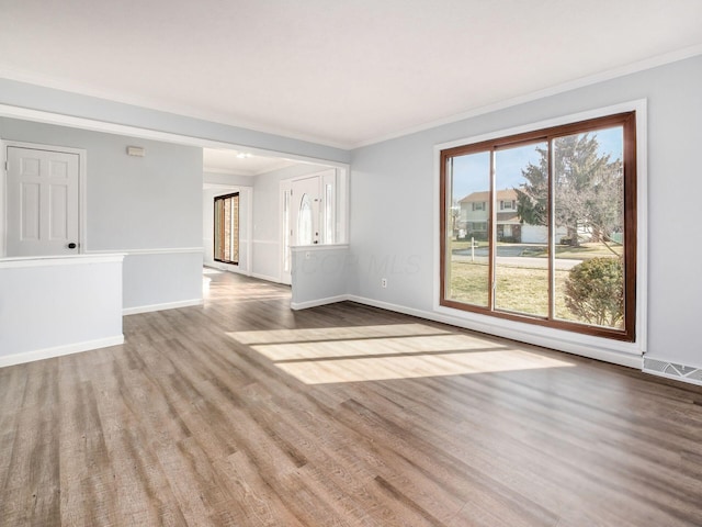 spare room with ornamental molding, visible vents, baseboards, and wood finished floors