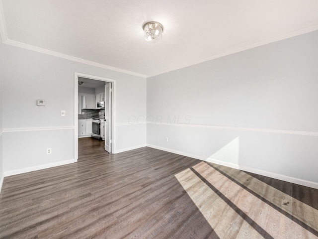 empty room featuring ornamental molding, dark wood-style flooring, and baseboards