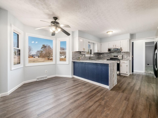 kitchen featuring visible vents, dark wood-style floors, appliances with stainless steel finishes, white cabinetry, and a sink