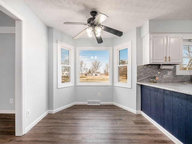 unfurnished dining area featuring visible vents, dark wood finished floors, a textured ceiling, and baseboards