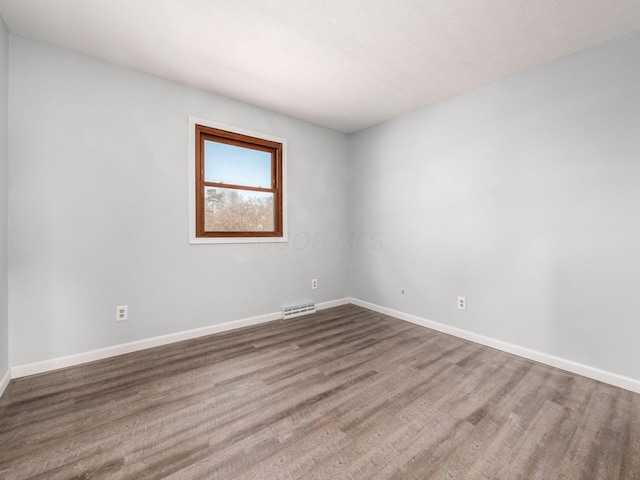 unfurnished room with wood finished floors, visible vents, and baseboards