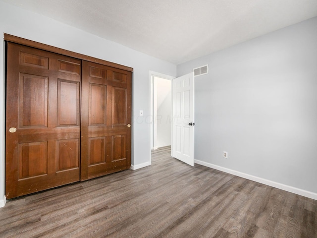 unfurnished bedroom with wood finished floors, visible vents, and baseboards