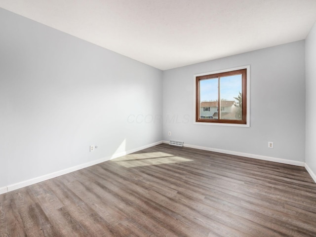 empty room featuring visible vents, baseboards, and wood finished floors