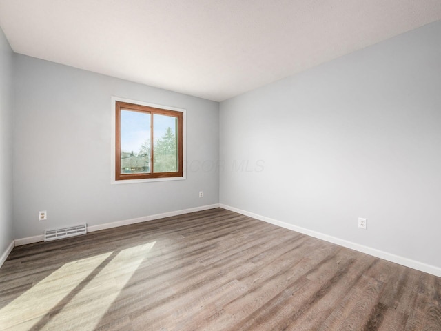 empty room with visible vents, baseboards, and wood finished floors