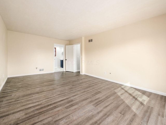 empty room featuring visible vents, baseboards, and wood finished floors