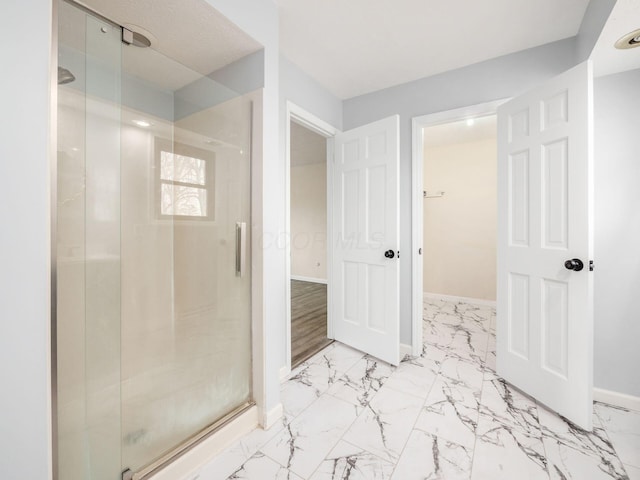 full bathroom with marble finish floor, a shower stall, and baseboards