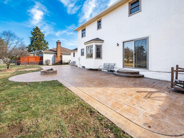 back of house with a patio, stucco siding, a lawn, an outdoor fire pit, and fence