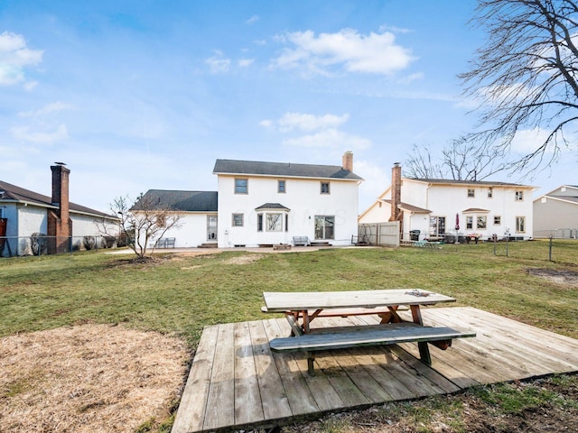 rear view of property with a deck, a yard, a chimney, and a fenced backyard