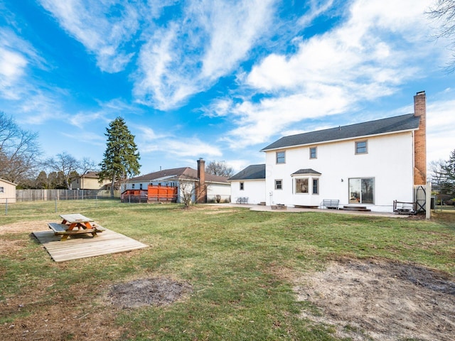 back of property with a patio, a fenced backyard, a lawn, stucco siding, and a chimney