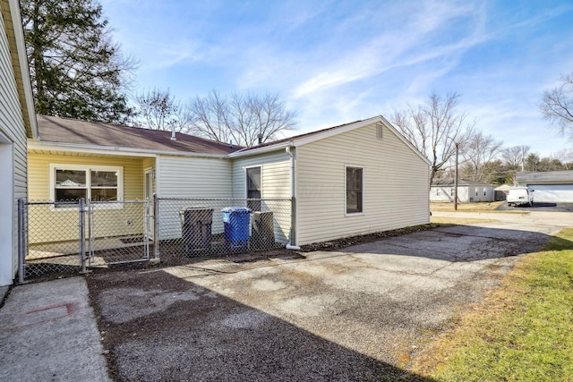 back of house featuring concrete driveway, fence, and a gate