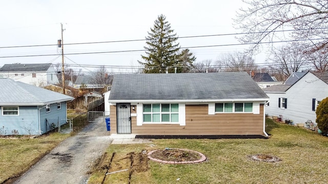 view of front of property with a shingled roof, aphalt driveway, and a front yard