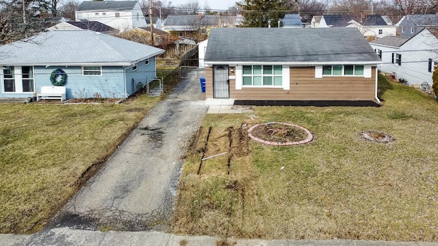 view of front of house with driveway, roof with shingles, and a front yard