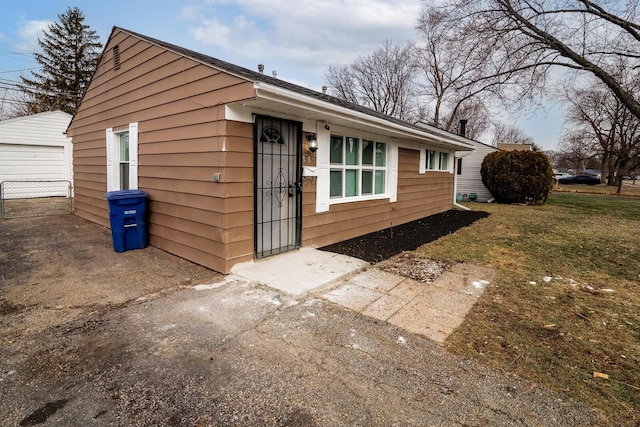 view of property exterior featuring an outdoor structure, a lawn, and a detached garage