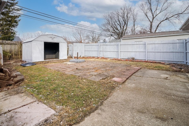 view of yard with a storage shed, a patio area, an outbuilding, and a fenced backyard