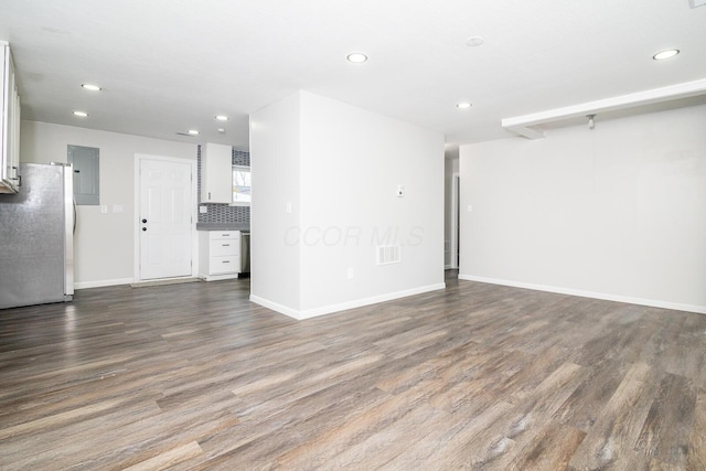 unfurnished living room with dark wood-type flooring, recessed lighting, and baseboards