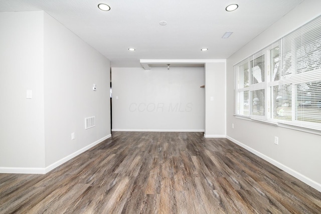 unfurnished room with wood finished floors, visible vents, and baseboards