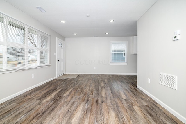 empty room featuring dark wood-type flooring, recessed lighting, visible vents, and baseboards