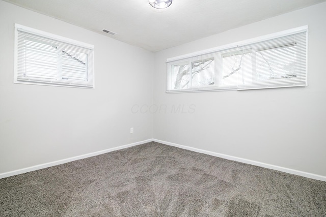 carpeted empty room featuring baseboards and visible vents