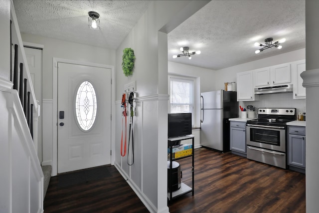 kitchen featuring under cabinet range hood, gray cabinets, dark wood-style floors, and stainless steel appliances