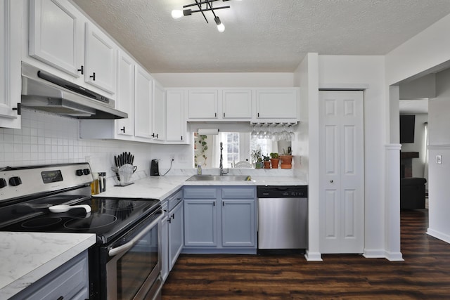 kitchen featuring dark wood-style floors, stainless steel appliances, light countertops, under cabinet range hood, and a sink