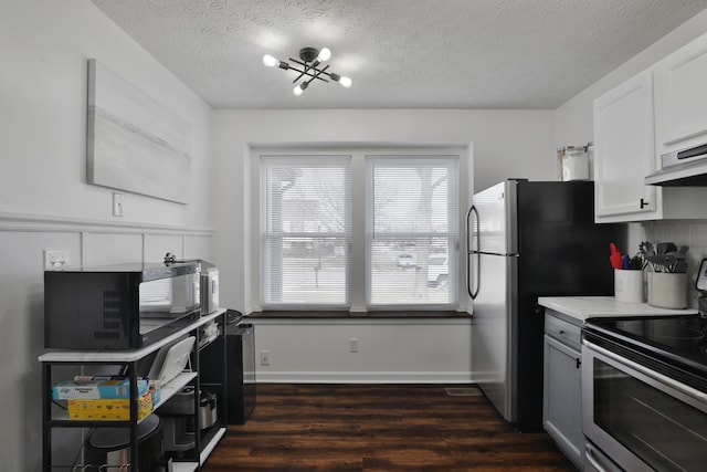 kitchen featuring dark wood-style floors, stainless steel electric range oven, light countertops, a textured ceiling, and under cabinet range hood