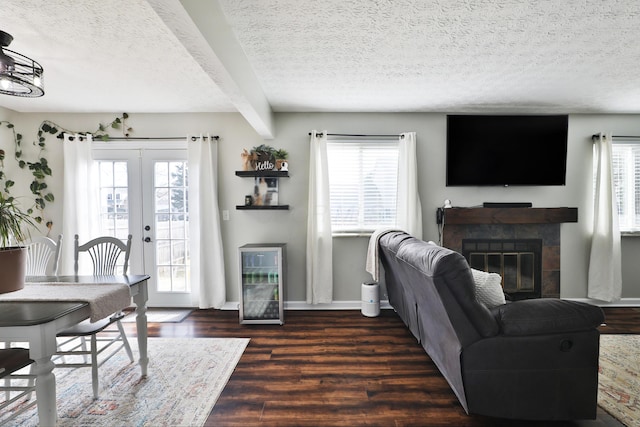 living room featuring a textured ceiling, french doors, dark wood-style flooring, and a tile fireplace