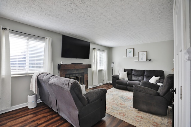 living room featuring dark wood-style floors, a tile fireplace, and baseboards