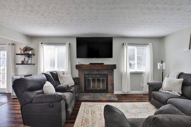 living area with dark wood-style flooring, a tile fireplace, and a wealth of natural light