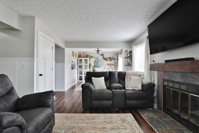 living area with a wainscoted wall, a fireplace, wood finished floors, and a textured ceiling