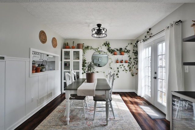 dining area featuring a textured ceiling, french doors, dark wood finished floors, and visible vents