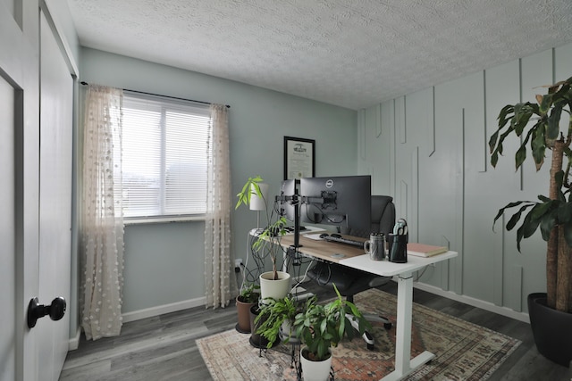 office area featuring a textured ceiling, baseboards, and wood finished floors