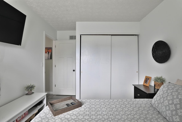 bedroom with a textured ceiling, a closet, and visible vents