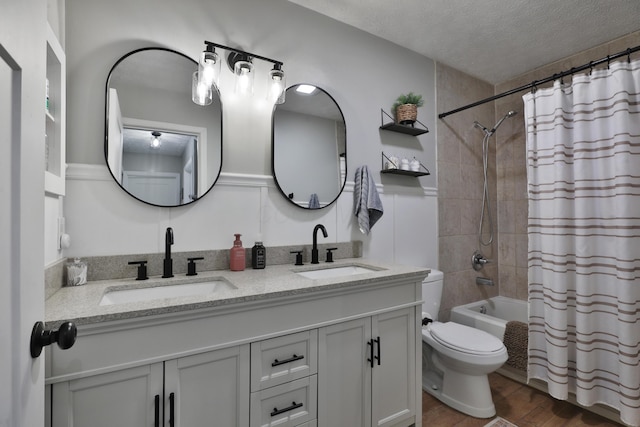 full bath with a textured ceiling, wood finished floors, shower / bath combo, and a sink