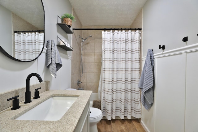 bathroom featuring a textured ceiling, toilet, wood finished floors, vanity, and shower / bath combination with curtain