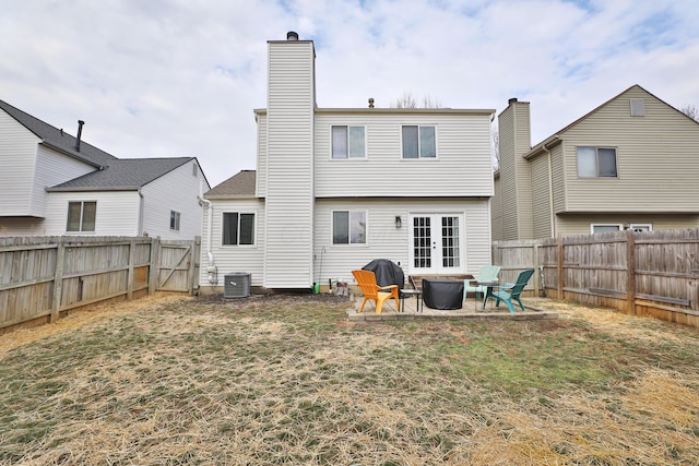 rear view of property with an outdoor fire pit, french doors, a fenced backyard, and a patio