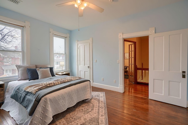 bedroom with dark wood-style floors, ceiling fan, and baseboards