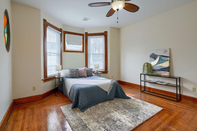 bedroom featuring a ceiling fan, wood-type flooring, visible vents, and baseboards