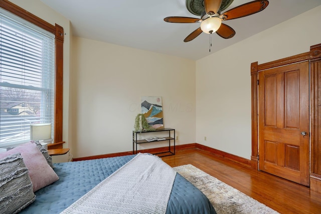 bedroom featuring a ceiling fan, baseboards, and wood finished floors